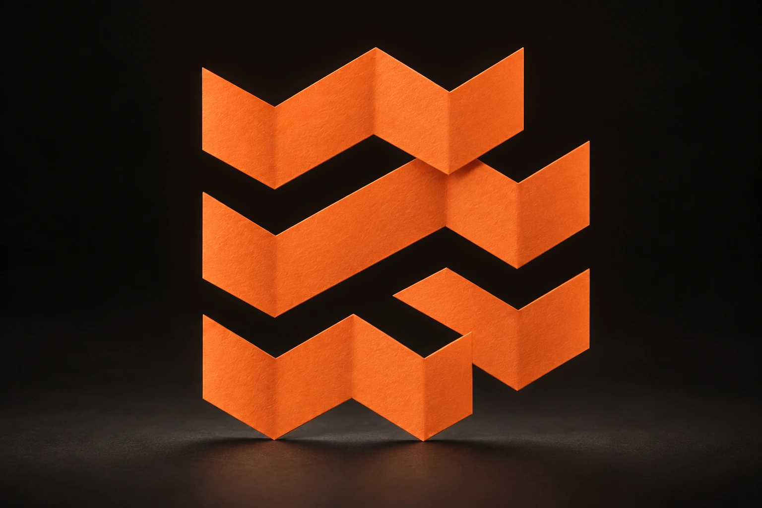 Le symbole Travel Tech Factory sculpté en papier plié orange